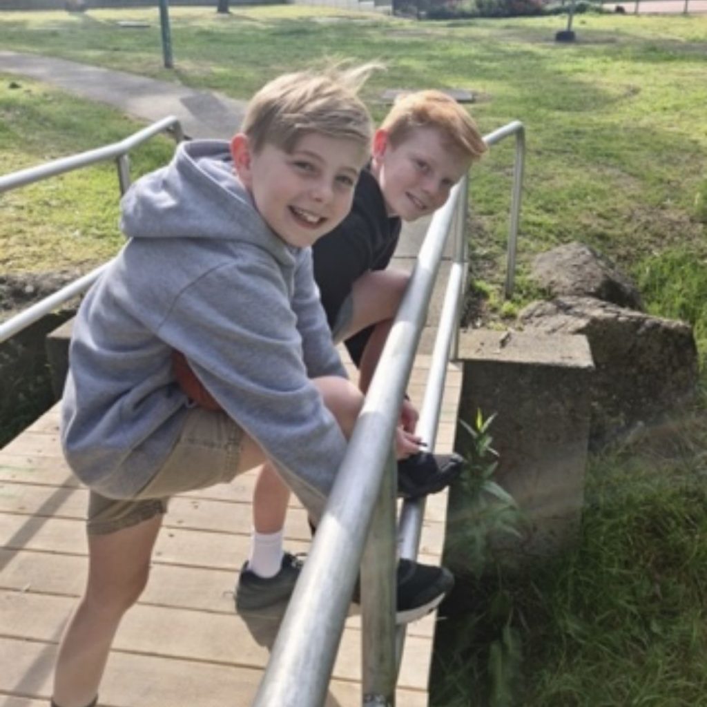 Boys lacing up shoes at park bridge, getting ready for the Be Wise Walk and looking to camera